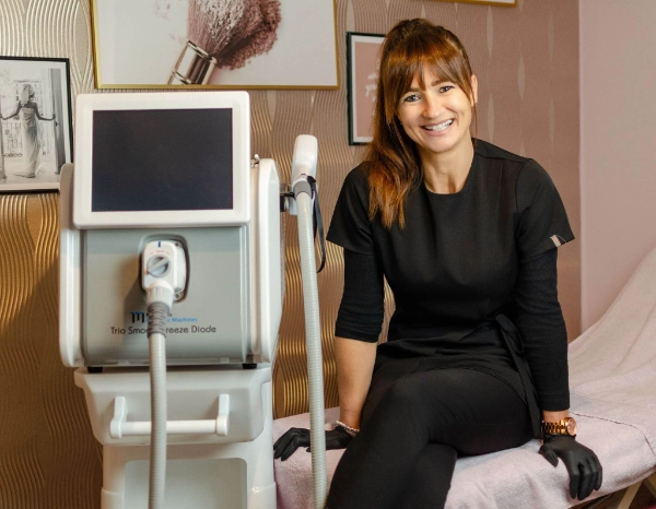 Jennie Gostling sitting with her laser machine, smiling.